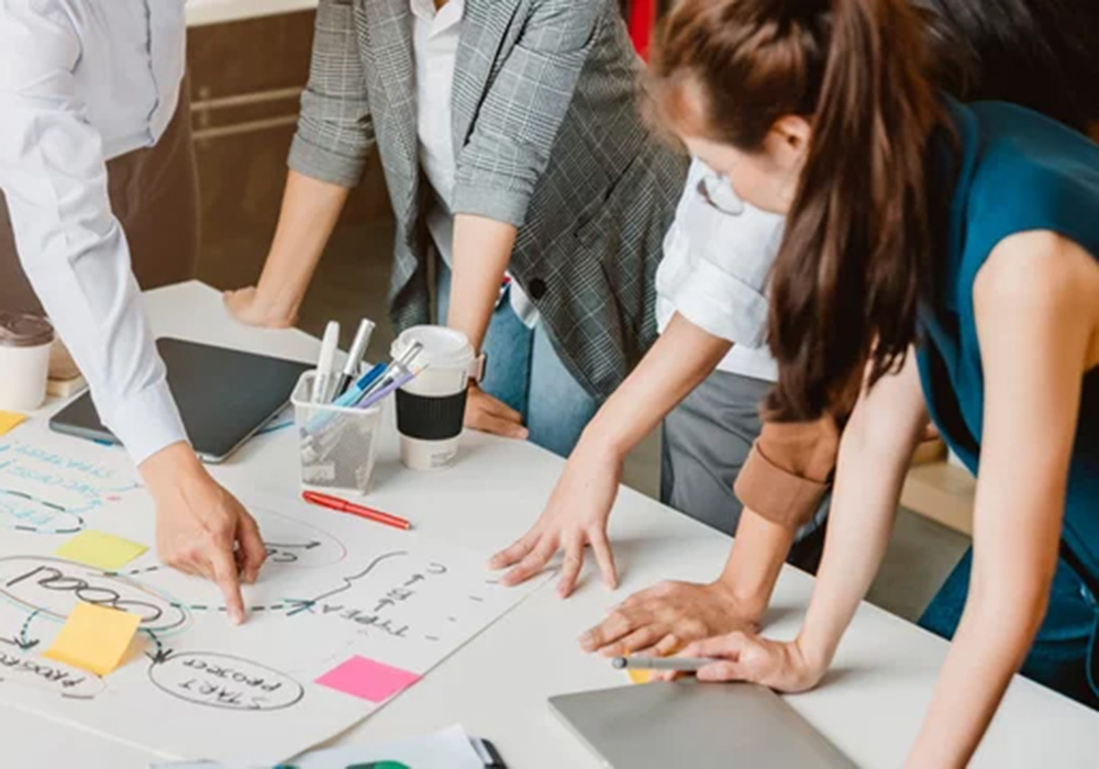 group of marketers gathered round a desk with post its and paper
