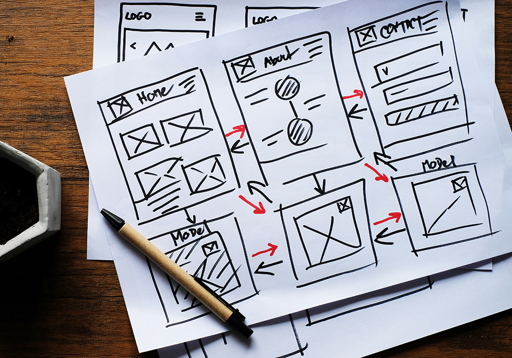 wireframes stacked on desk with pen on top