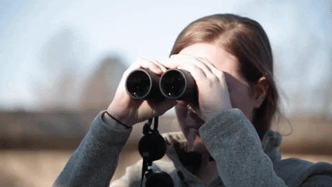 woman with ginger hair looking through binoculars